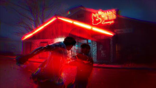 Screenshot from "Halloween: The Game," showing two characters fighting outside a neon-lit building at night.