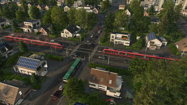 Screenshot from Transport Fever 3 showing a vibrant city intersection with trains, buses, and houses surrounded by greenery.