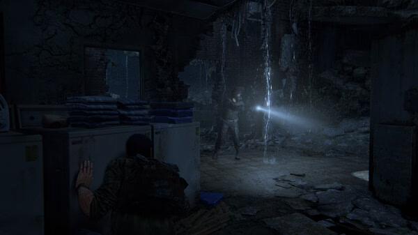 A dimly lit room in 'The Last of Us Part I' screenshot shows a character hiding from an enemy with a flashlight.