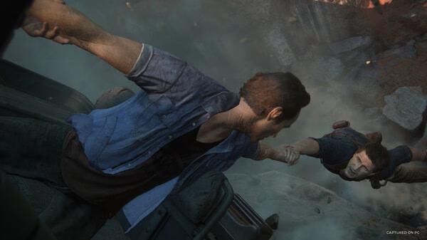 Screenshot from UNCHARTED: Legacy of Thieves Collection showing two characters gripping hands amidst a dramatic action scene.