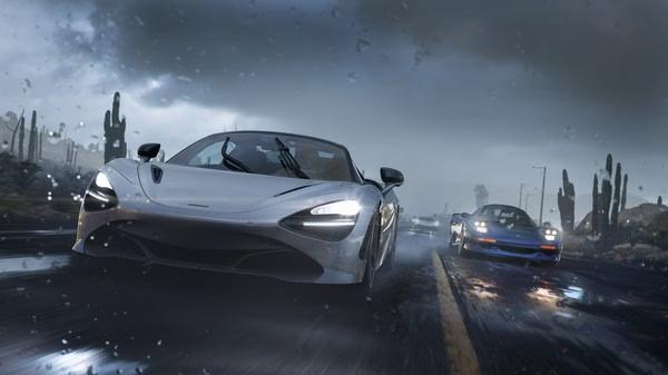 Screenshot from Forza Horizon 5 showing two sleek sports cars racing on a wet road under a stormy sky with cacti in the background.