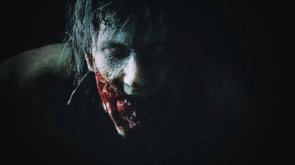 Resident Evil 2 screenshot: A zombie emerges from the shadows, showcasing the game's intense horror atmosphere.
