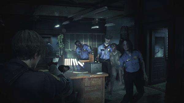 Resident Evil 2 screenshot: A character aims a gun at approaching zombie police officers in a dimly lit office room.