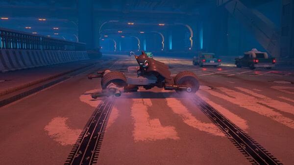 A screenshot from LEGO® Batman™: Legacy of the Dark Knight showing Batman on a Batcycle in a dimly lit underground tunnel.