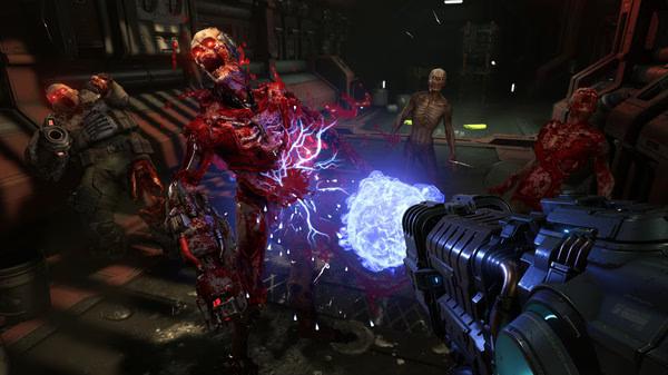 DOOM Eternal screenshot: A player wields a weapon emitting energy against grotesque, attacking demons in a dark, industrial environment.