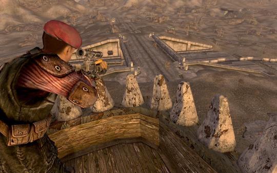Screenshot from Fallout: New Vegas showing a character in a red beret aiming a sniper rifle from a wooden tower overlooking a desert landscape.