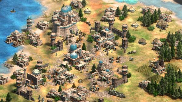 Screenshot from Age of Empires II showing a bustling medieval town with various buildings and units by the sea.