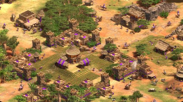 A screenshot from Age of Empires II showing a fortified village with farms, towers, and units in a desert landscape.