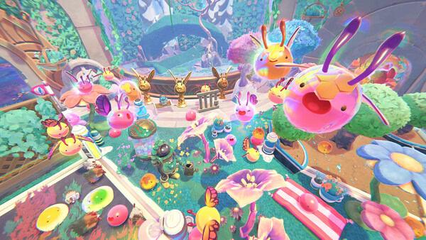 A colorful screenshot from Slime Rancher 2 showing vibrant slimes, flowers, and decorations in a lush garden environment.