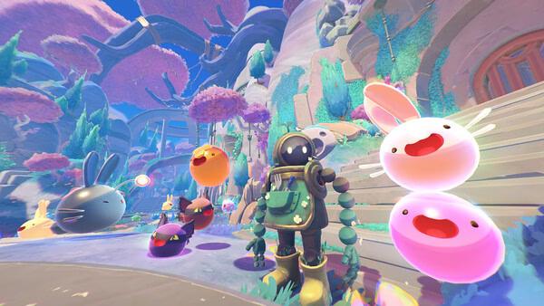 Screenshot from Slime Rancher 2 shows a rancher surrounded by colorful slimes and vibrant alien flora.