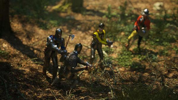 Screenshot from Half Sword: Four armored knights in a forest, two wielding axes, others on guard, in a tense standoff.