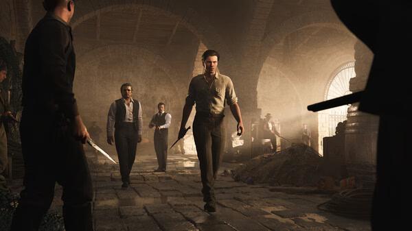 Screenshot from Mafia: The Old Country showing a tense standoff in a dimly lit warehouse, with characters holding weapons.