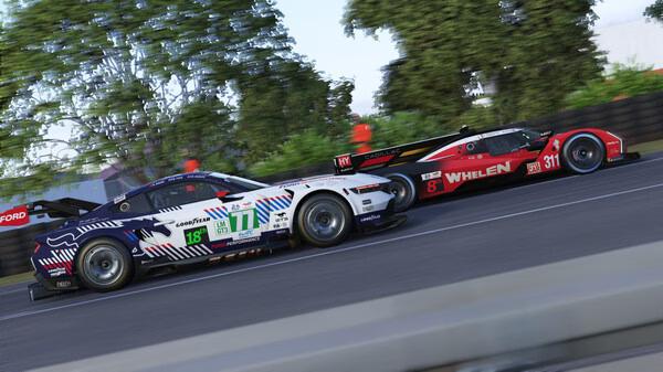 Le Mans Ultimate screenshot: Two race cars, #77 and #31, speed side by side on a track lined with green trees.