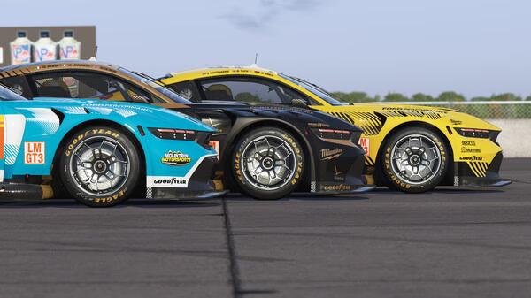 Screenshot from Le Mans Ultimate showing three sports cars lined up on the racetrack, featuring detailed designs and sponsor logos.