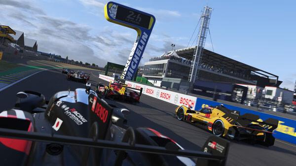Le Mans Ultimate screenshot: Multiple race cars speed around a track, passing under a Michelin sign at a racing event.
