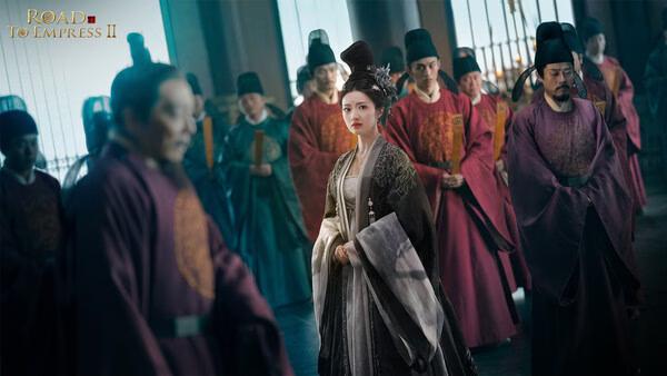 Screenshot from Road to Empress II showing a central character in regal attire surrounded by attendants in a grand hall.