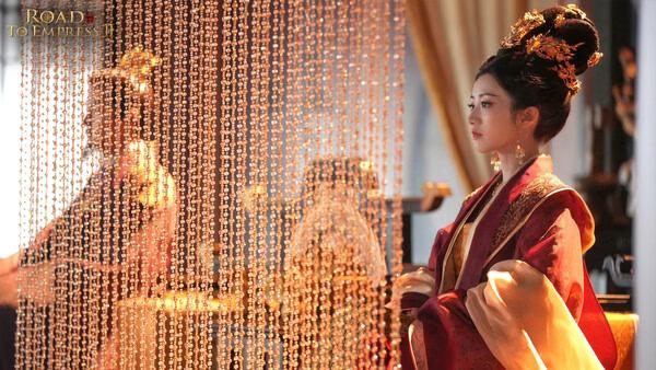 Screenshot from Road to Empress II showing two characters in elaborate royal attire behind golden beaded curtains.