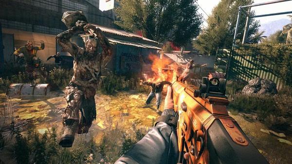Screenshot from Dying Light showing a player aiming a rifle at a zombie with a flaming background in an outdoor setting.