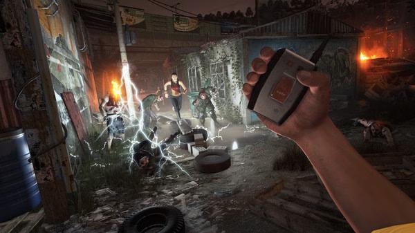 Dying Light screenshot: A hand holds a detonator in the foreground while zombies are electrified in a dark, rundown alley.