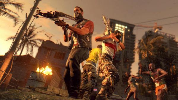 Dying Light screenshot: Survivors armed with weapons face approaching zombies in a fiery urban setting during sunset.