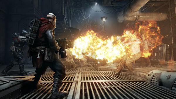 Warhammer 40,000: Darktide screenshot showing a player character firing a flamethrower at oncoming enemies in an industrial setting.