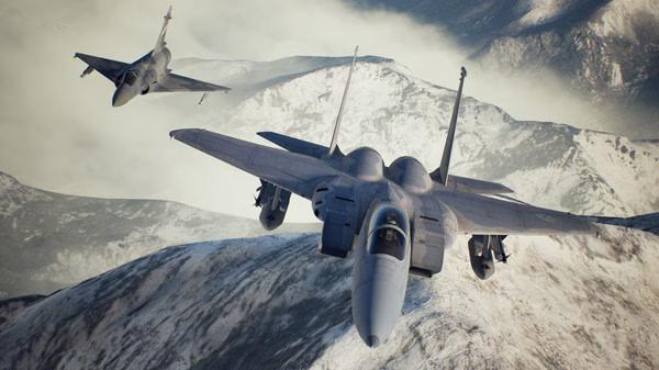 ACE COMBAT 7: SKIES UNKNOWN screenshot showing two fighter jets soaring over snow-covered mountains under a cloudy sky.