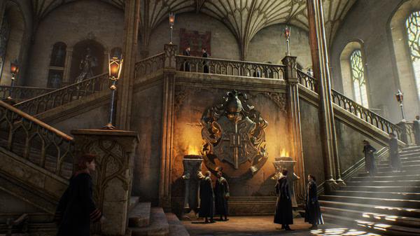 Screenshot from Hogwarts Legacy showing students and faculty gathering in the grand, ornate entrance hall with a large crest.
