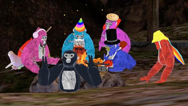 Gorilla Tag screenshot: Colorful gorillas in party hats gather around a campfire in a forest setting.