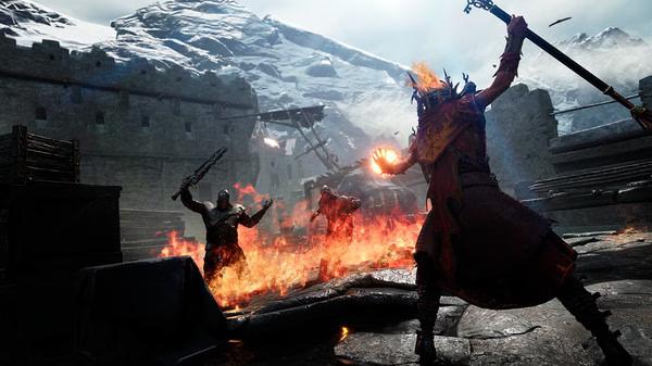 Warhammer: Vermintide 2 screenshot: A fiery battle scene with a mage casting spells against foes in a snowy fortress.