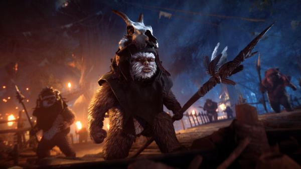 STAR WARS Battlefront II screenshot of Ewoks in a forest at night, holding spears and wearing skull helmets, surrounded by glowing torches.