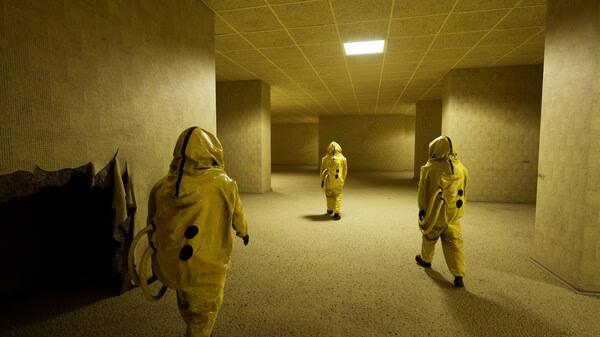 Screenshot from Backrooms: Escape Together showing three figures in yellow hazmat suits walking through dimly lit, maze-like corridors.
