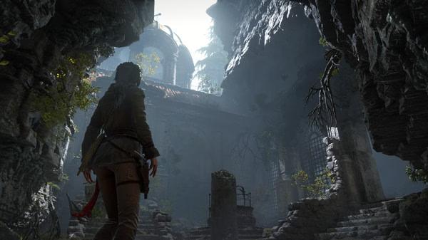 Screenshot from Rise of the Tomb Raider game showing a character exploring a shadowy, ancient stone ruin with overgrown foliage.