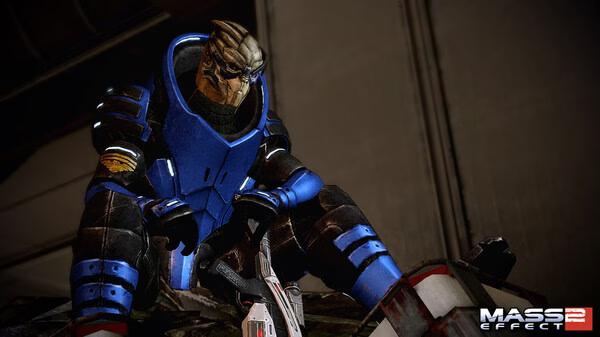 Mass Effect 2 screenshot: A character in blue armor crouches with a weapon, ready for action in a sci-fi setting.