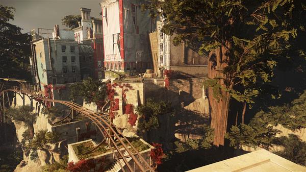 Dishonored 2 screenshot: A scenic view of a city with tall buildings and lush trees, featuring a rail track over a cliff.