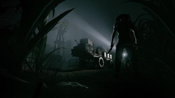 Outlast 2 screenshot: A shadowy figure holding a weapon approaches a cart loaded with hay under eerie moonlight in a dark rural setting.