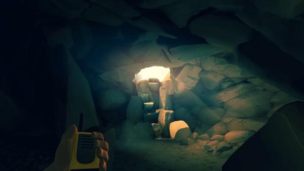 A Firewatch screenshot showing a hand holding a walkie-talkie inside a rocky cave with sunlight streaming through the exit.