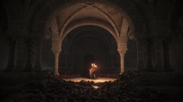 Screenshot from A Plague Tale: Innocence showing a character holding a torch in a dark stone archway surrounded by rats.