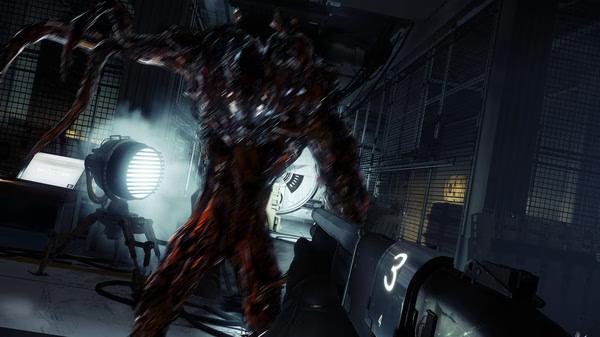 A screenshot from Prey showing a player aiming a shotgun at a monstrous alien in a dimly lit, metallic room.