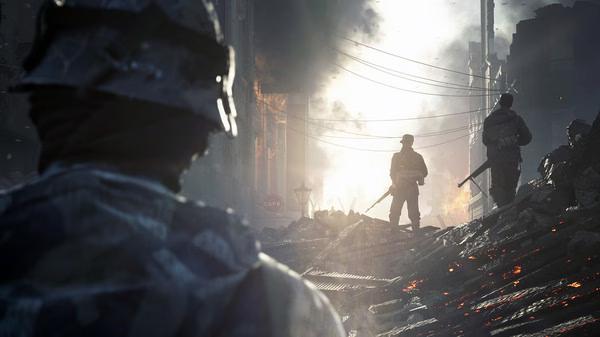 Battlefield V screenshot: Soldiers navigate a war-torn street with debris, fire, and smoke under a bright, hazy sky.