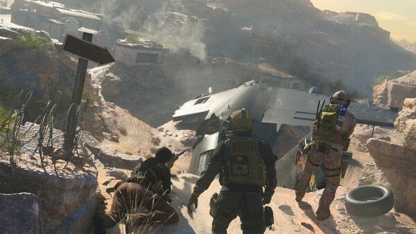 Screenshot from Call of Duty: Modern Warfare III shows soldiers near a crashed aircraft in a rocky desert landscape.