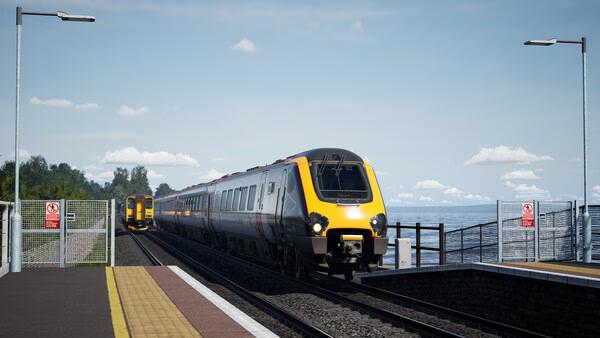 Train Sim World 6 screenshot: Two modern trains pass each other on a coastal track under a clear sky.