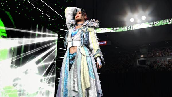 A WWE 2K26 screenshot showing a wrestler in a detailed outfit posing confidently on the stage under bright lights.