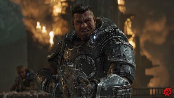 A Gears of War: E-Day screenshot showing an armored soldier wielding a gun, with a burning building in the background.
