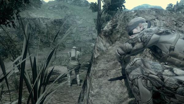 A screenshot from METAL GEAR SOLID: MASTER COLLECTION Vol.2 shows a camouflaged soldier crouching behind a rock, observing another soldier.