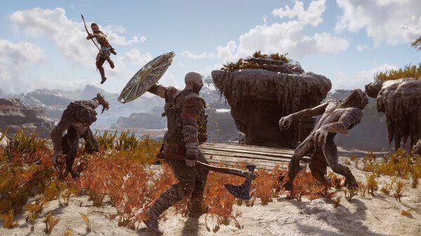A screenshot from God of War Ragnarök showing Kratos battling enemies with an axe and shield in a rocky, grassy landscape.
