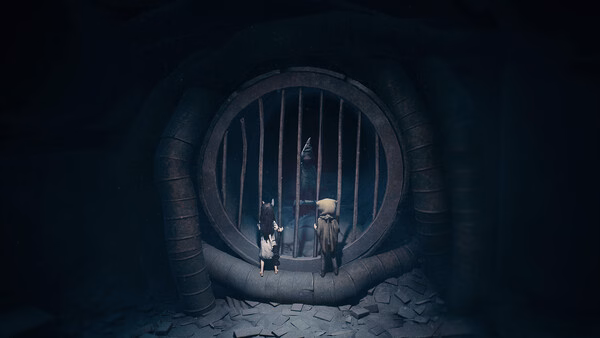 Screenshot from REANIMAL: Two characters stand in front of a large, circular barred gate in a dimly lit, mysterious setting.