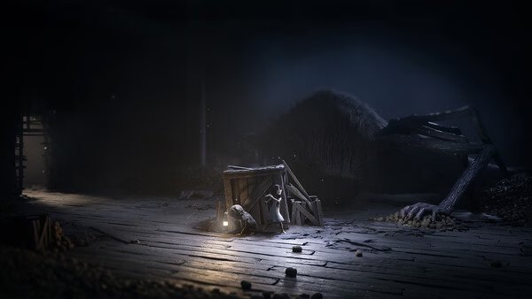 Screenshot from REANIMAL showing a small creature near a wooden crate and lantern, with a giant animal corpse in a dimly lit room.