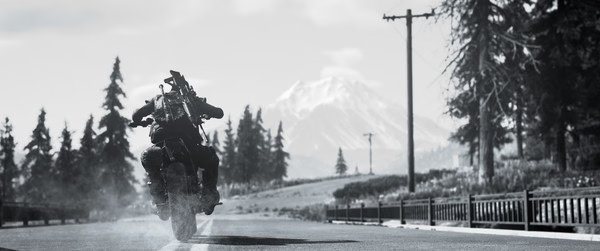 A Days Gone screenshot showing a biker speeding down a deserted road with mountains in the background.