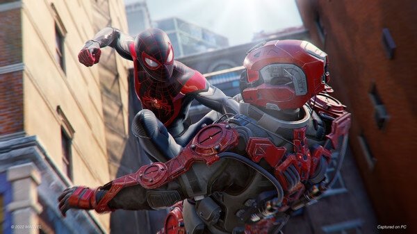 Screenshot from Marvel’s Spider-Man: Miles Morales showing Spider-Man mid-air, kicking an armored enemy on a city rooftop.