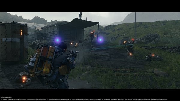 Screenshot from DEATH STRANDING DIRECTOR'S CUT showing Sam Bridges in combat, firing at enemies near a rugged campsite in a grassy landscape.
